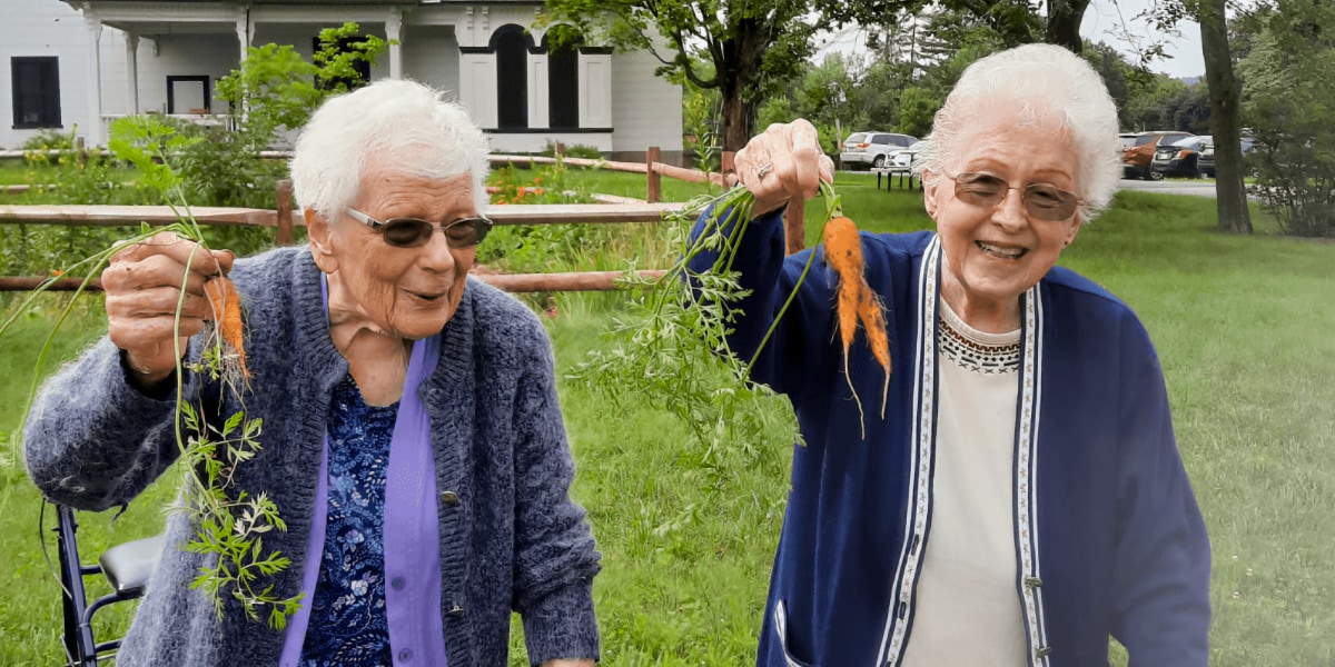 women with carrots in garden